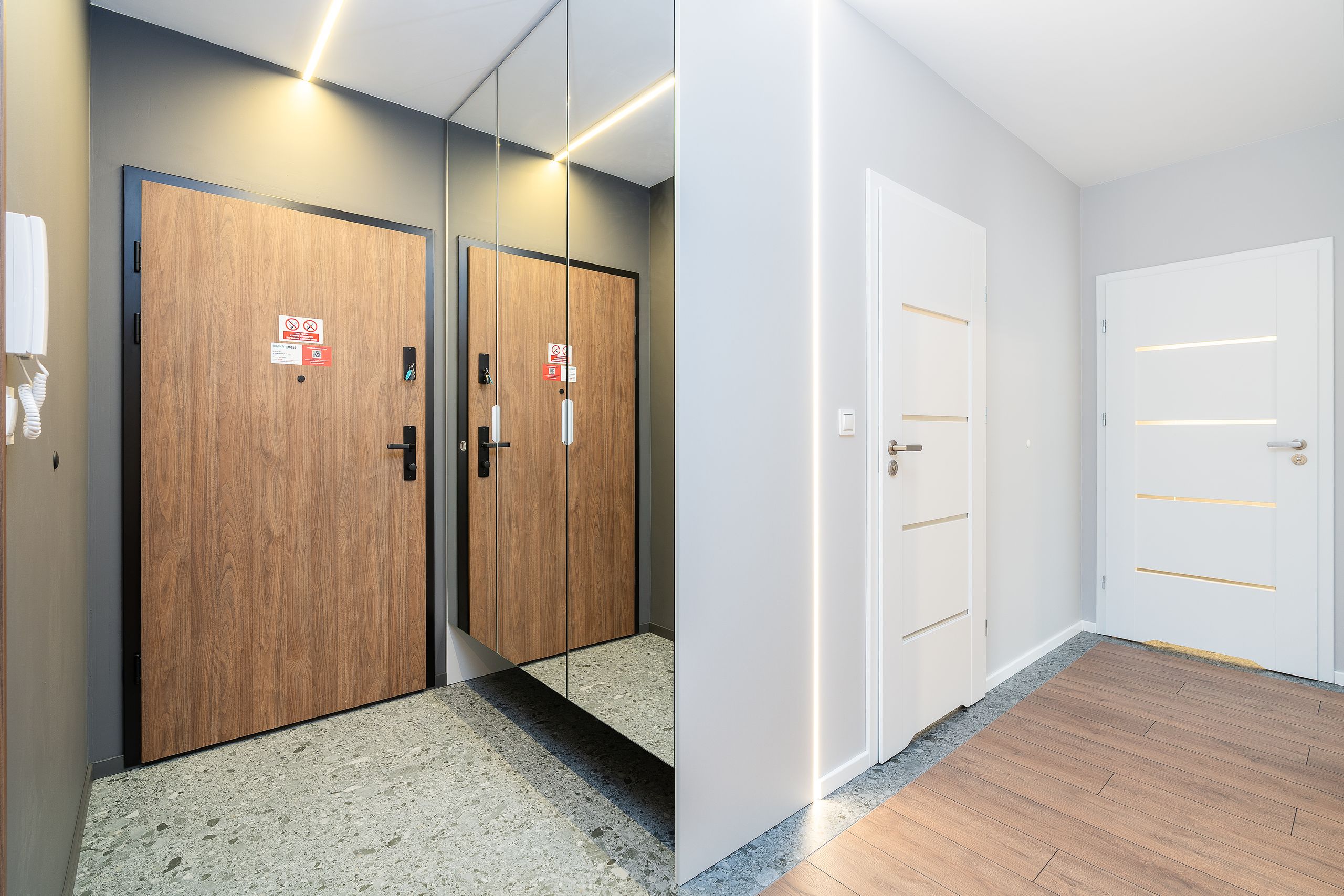A minimalist hallway with wooden and white doors, showcasing modern interior design.