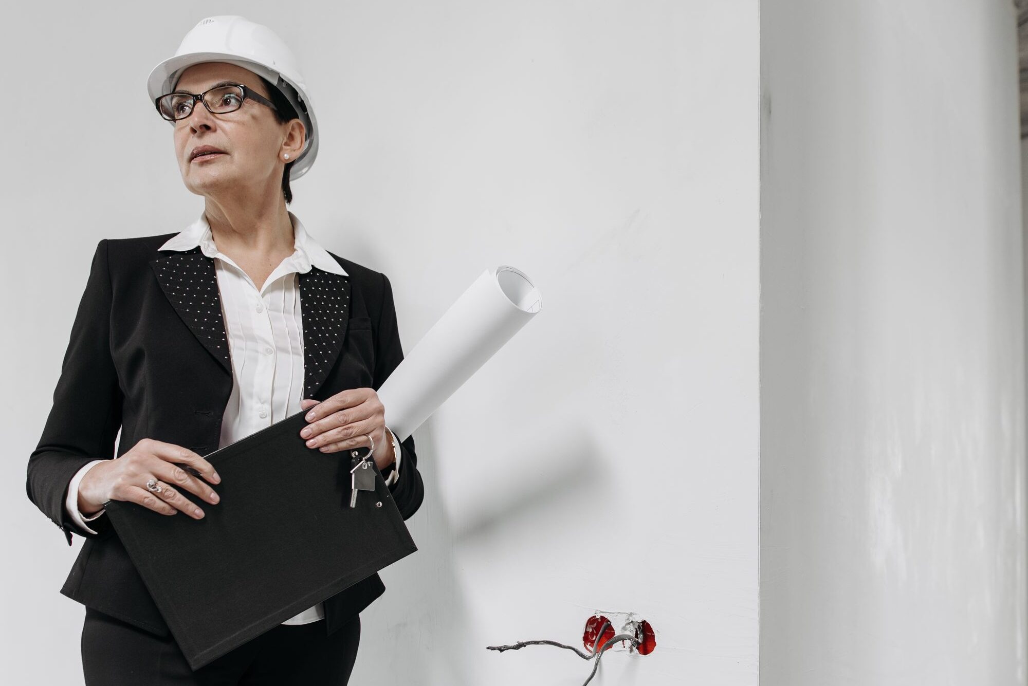 Professional woman in hard hat evaluating building interior. Ideal for construction and real estate themes.